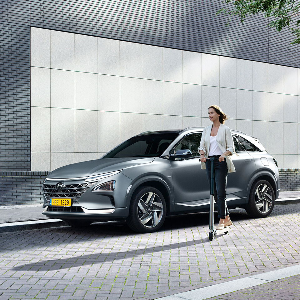 Woman passing by car on electric scooter