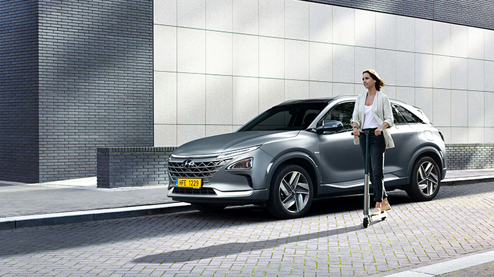 Woman passing by car on electric scooter