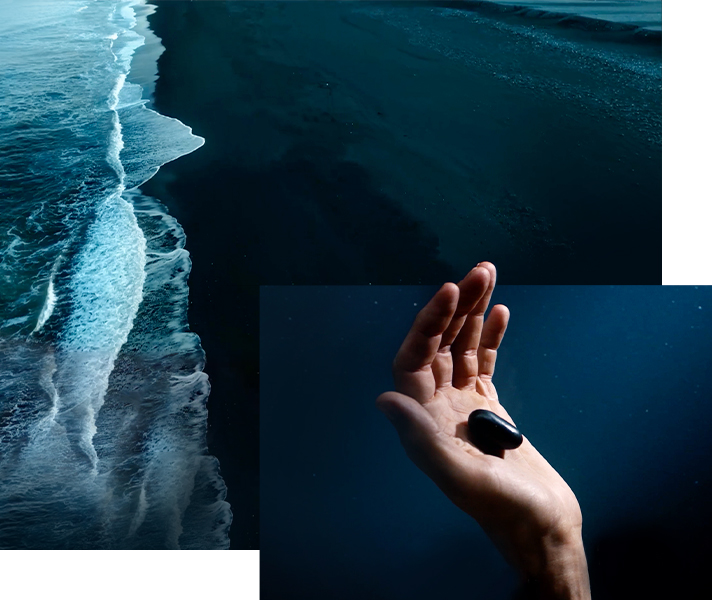 검은 해변가와 검은 조약돌을 들고 있는 손