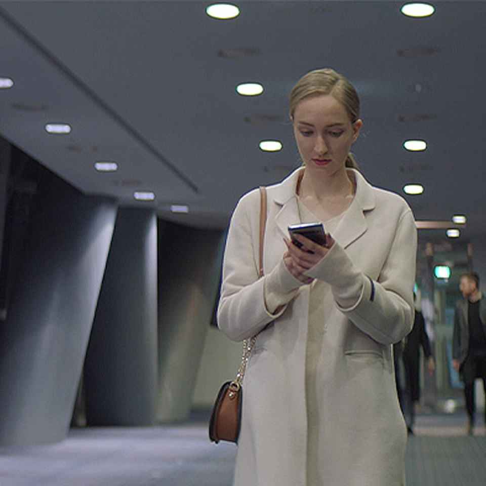 빌딩 안에서 통화를 하며 걷고 있는 플로레