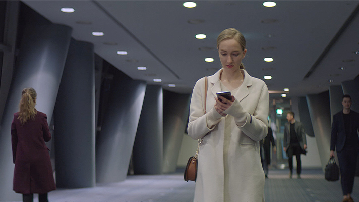 빌딩 안에서 통화를 하며 걷고 있는 플로레