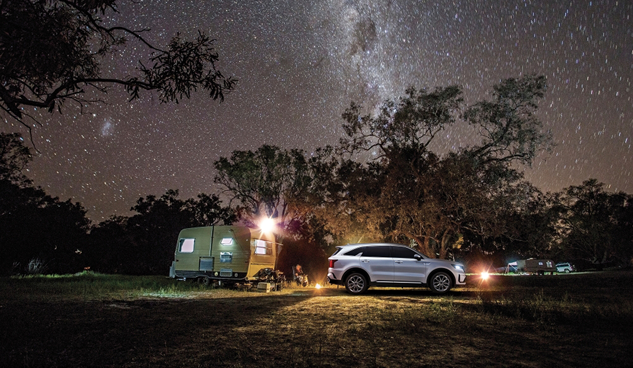 캠핑장에 서있는 스노우 화이트 펄 색상 기아 쏘렌토의 모습