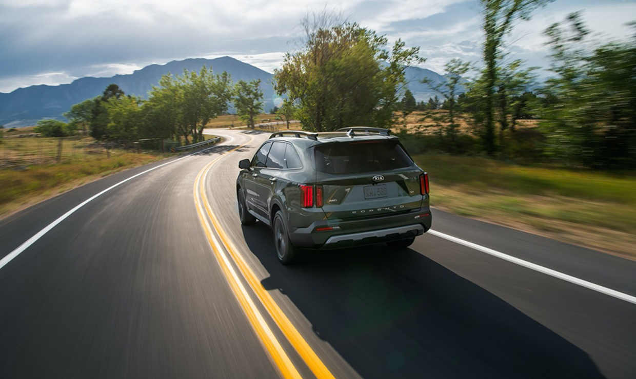 도로 주행중인 사파이어 블루 색상 기아 쏘렌토의 후면 모습