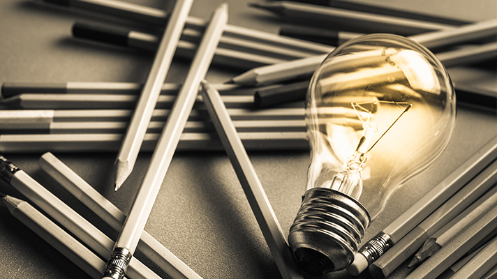 연필 더미와 불이 켜진 전구의 모습