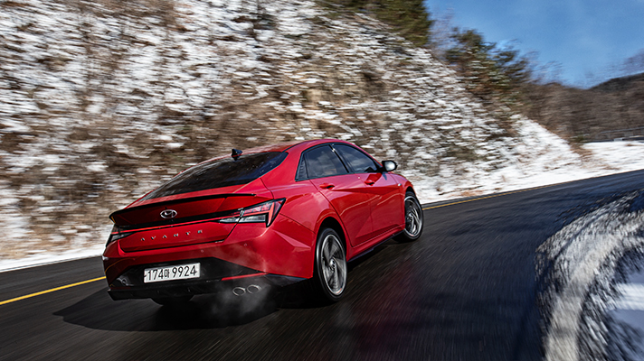 Rear angle view of red Hyundai Elantra N Line driving uphill