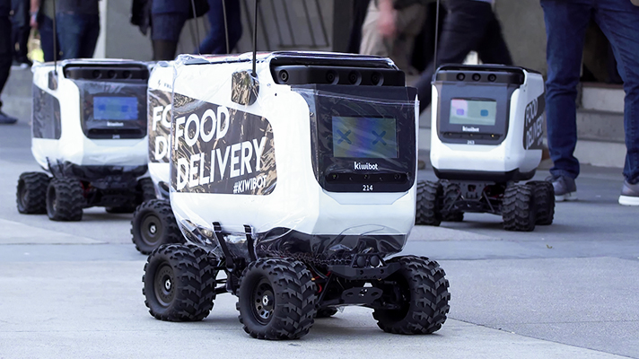 4 Kiwibots delivering food along the sidewalk