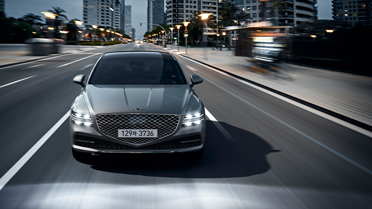 도로를 주행 중인 제네시스 G80의 앞모습