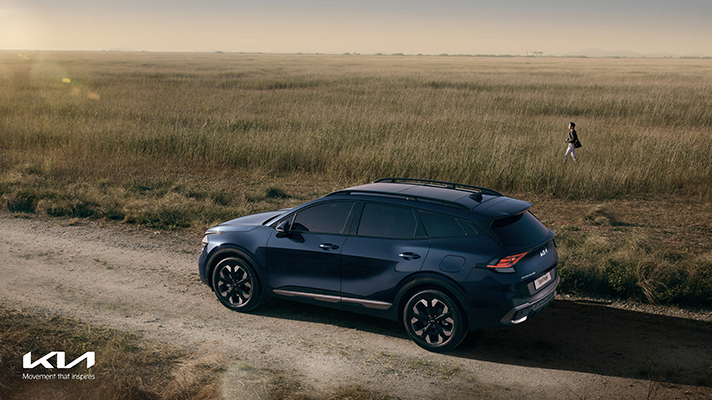 황금빛 들판의 길 위에 주차되어 있는 기아 신형 스포티지 모습