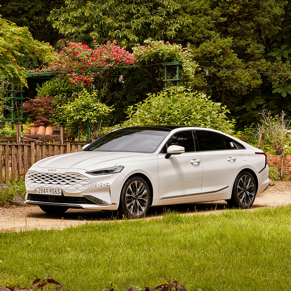 Kia K8 parked in the front yard of a country house