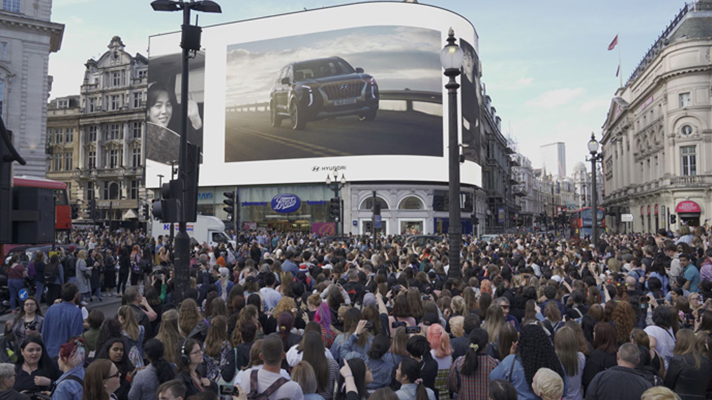 많은 인파가 밀집된 해외 광장 전광판에 현대차가 광고되고 있는 모습