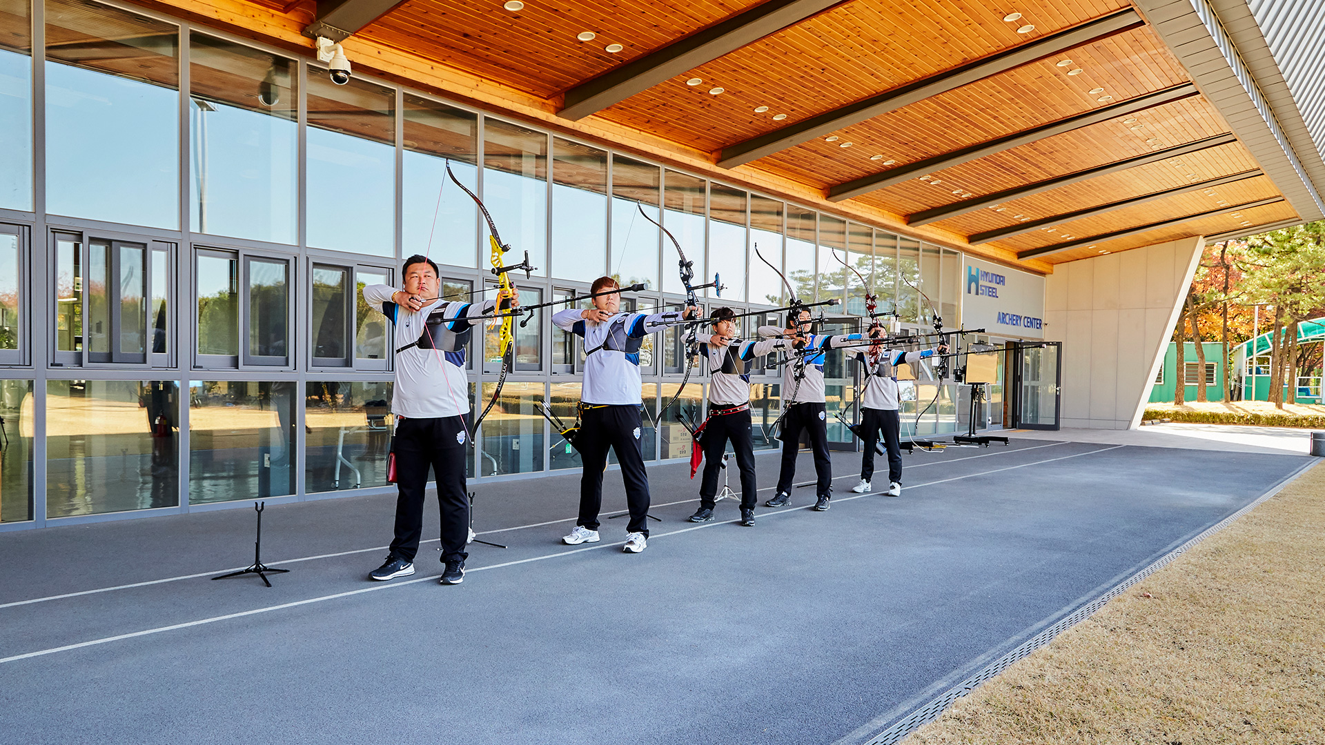 Men's archery team members pulling their bowstrings side by side