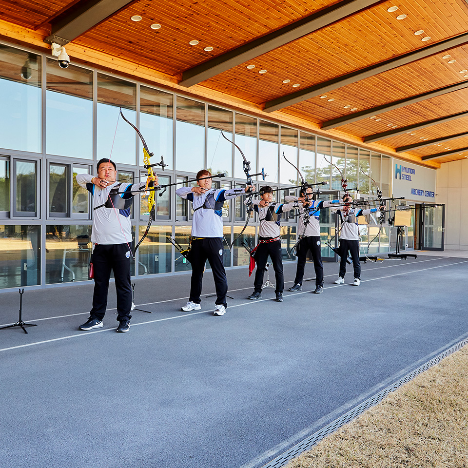 Men's archery team members pulling their bowstrings side by side