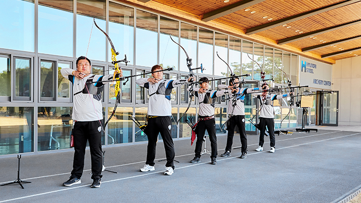 Men's archery team members pulling their bowstrings side by side