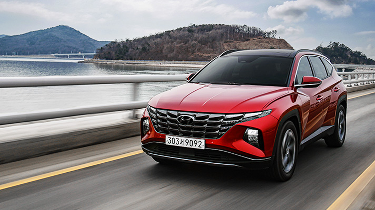 Front angle view of red Hyundai Tucson driving on road