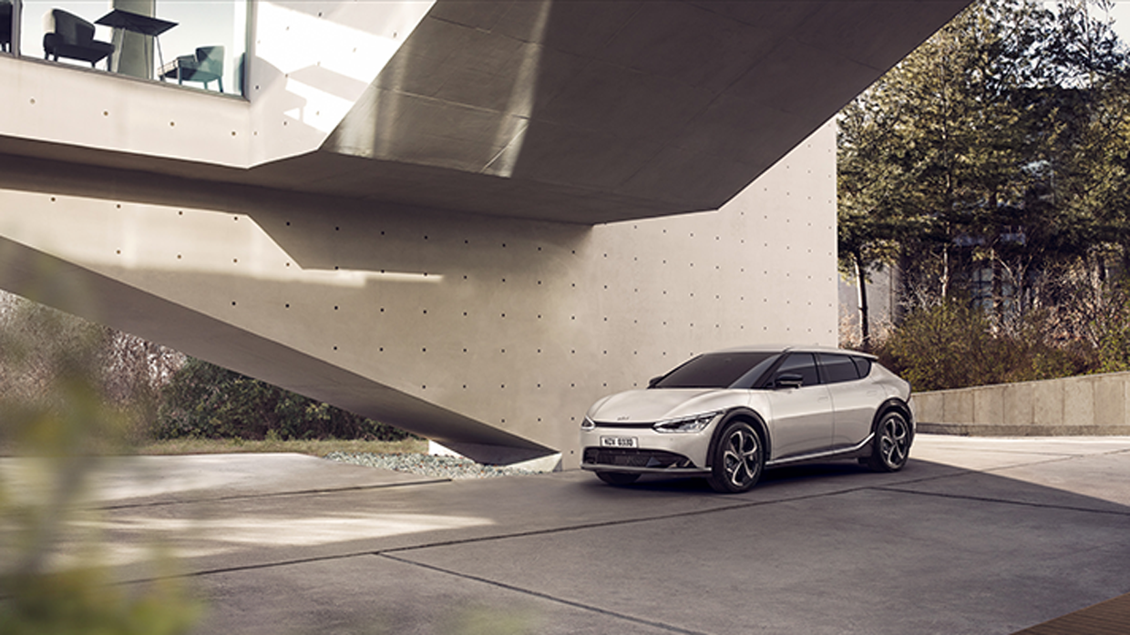 모던 빌딩 앞에 서 있는 기아 EV6 측면 앵글 모습