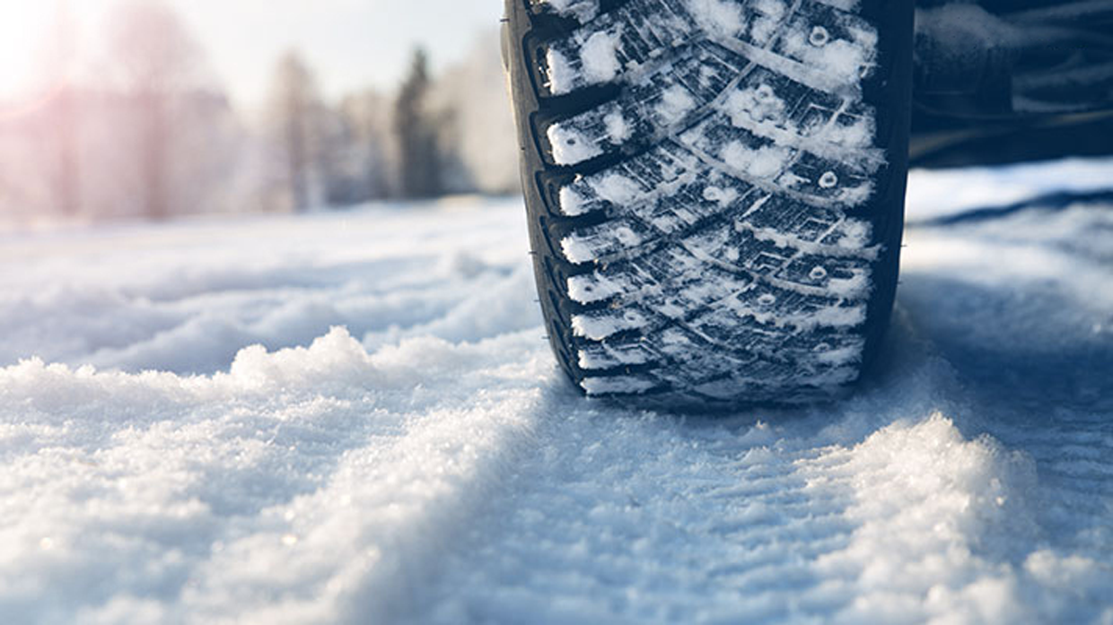 Image with tires and tire marks on a snowy road in focus