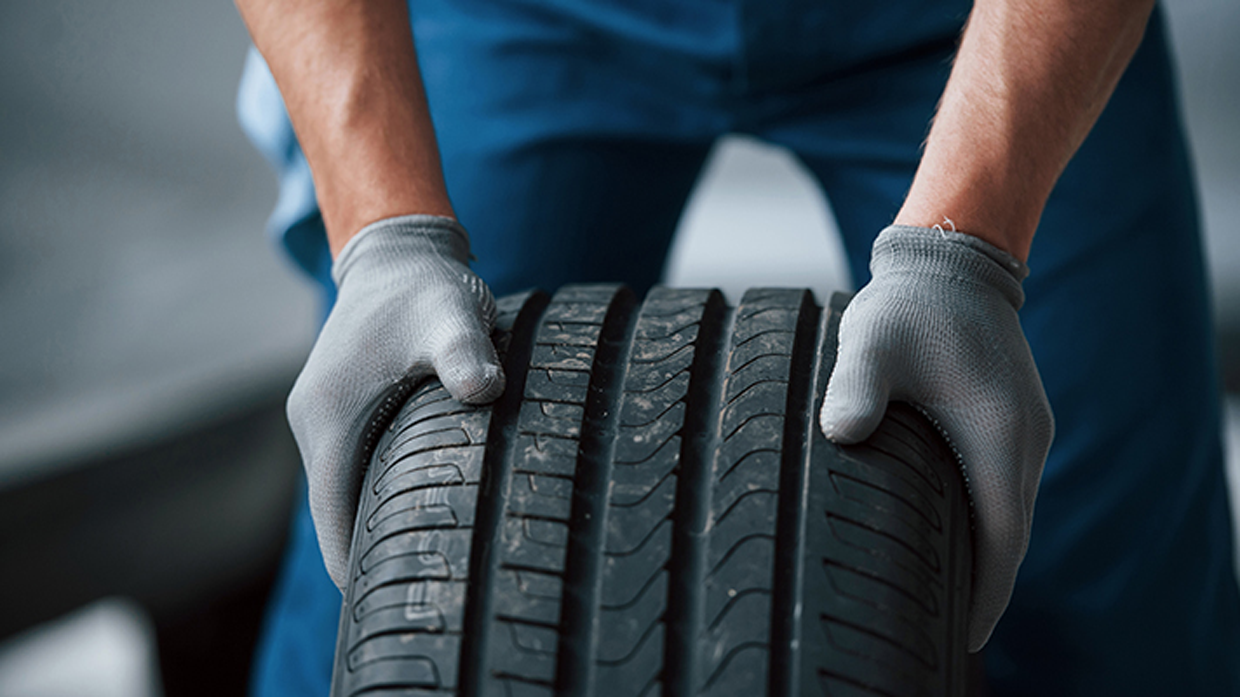 Image of a gloved mechanic moving a tire