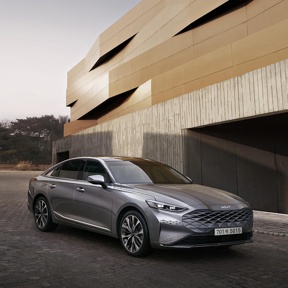 모던 빌딩 앞에 주차된 기아 K8 측면 앵글 모습