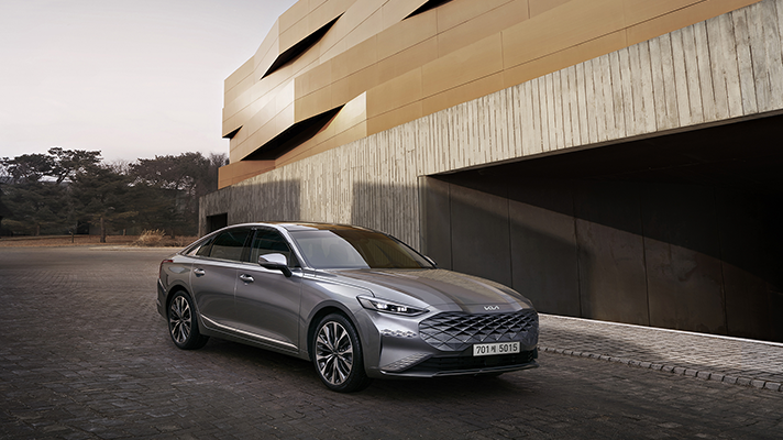 모던 빌딩 앞에 주차된 기아 K8 측면 앵글 모습