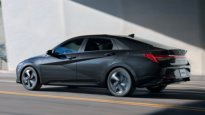 도로를 주행중인 어두운 회색의 아반떼 뒷모습