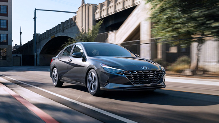 도로를 주행중인 어두운 회색의 아반떼 앞모습