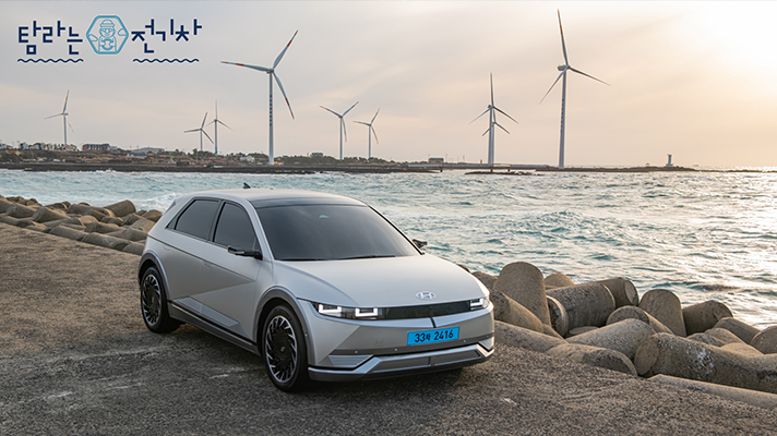 풍력발전이 돌아가는 바닷가에 주차된 아이오닉의 측면