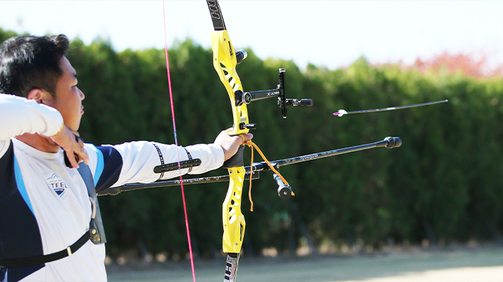 Side view of the national archery team shooting a bow