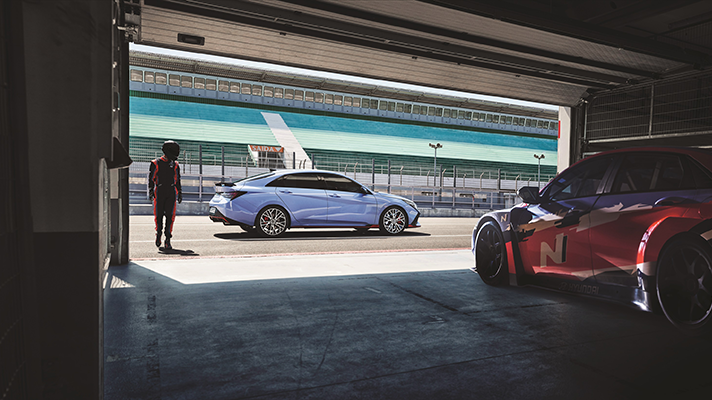 서킷에 주차된 현대자동차 아반떼 N과 옆에 서 있는 레이서