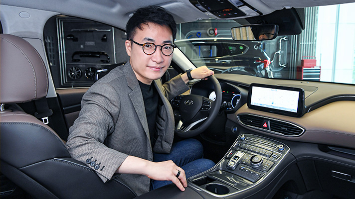 Senior Research Engineer Kim Young-Hoon, responsible for the GUI holding steering wheel and looking back
