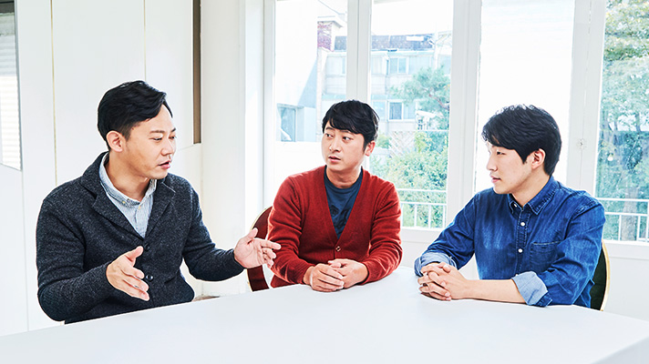 테이블에 앉아 인터뷰 중인 3명의 히든라이팅 기술 개발진