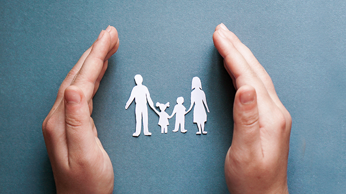 종이로 만든 4인가족의 형상을 양 손으로 감싸고 있는 모습