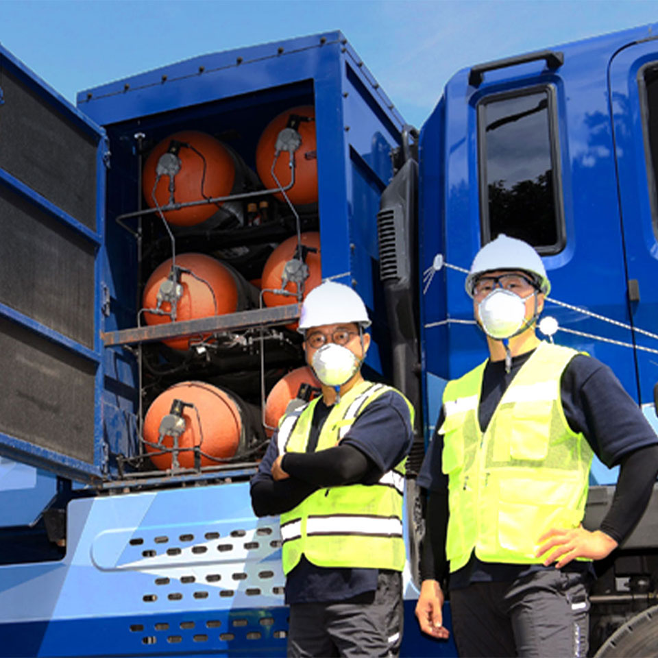 수소청소트럭 앞에 서 있는 두 명의 환경미화원