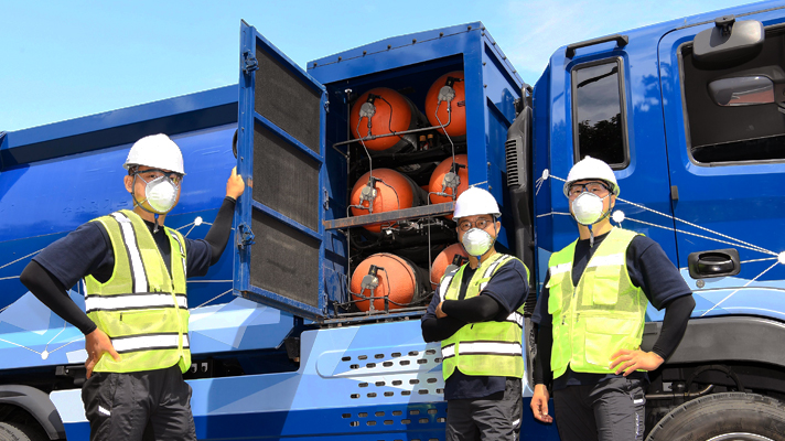 수소청소트럭 앞에 서 있는 세 명의 환경미화원