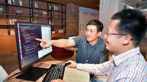 A Hyundai Mobis employee who is pointing at the monitor, and a colleague who is watching from the side