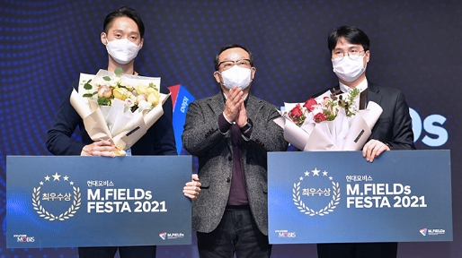 Two employees of Hyundai Mobis who won the grand prize at the M.FIELDs Festa and a presenter clapping in the meantime