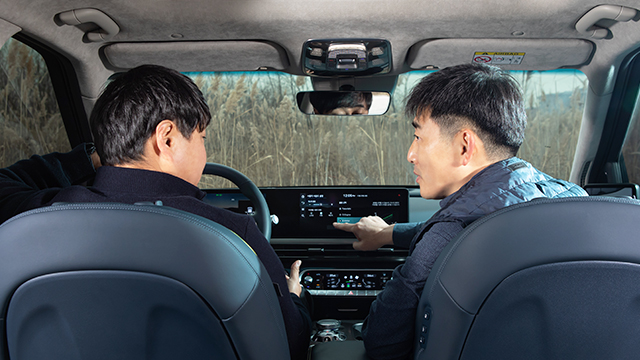 인포테인먼트 시스템 화면을 가리키며 전기차 액티브 사운드 디자인을 설명하는 두 연구원