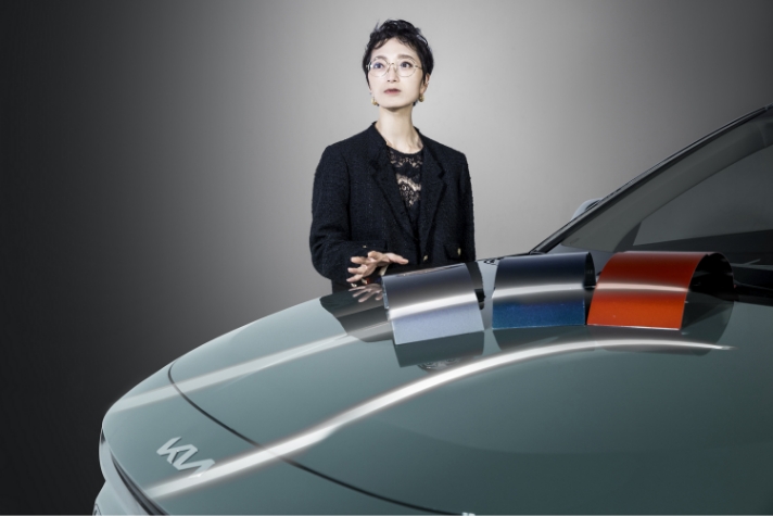 Jang Su-jin, a senior researcher, is explaining with silver and blue and red samples on Niro's bonnet