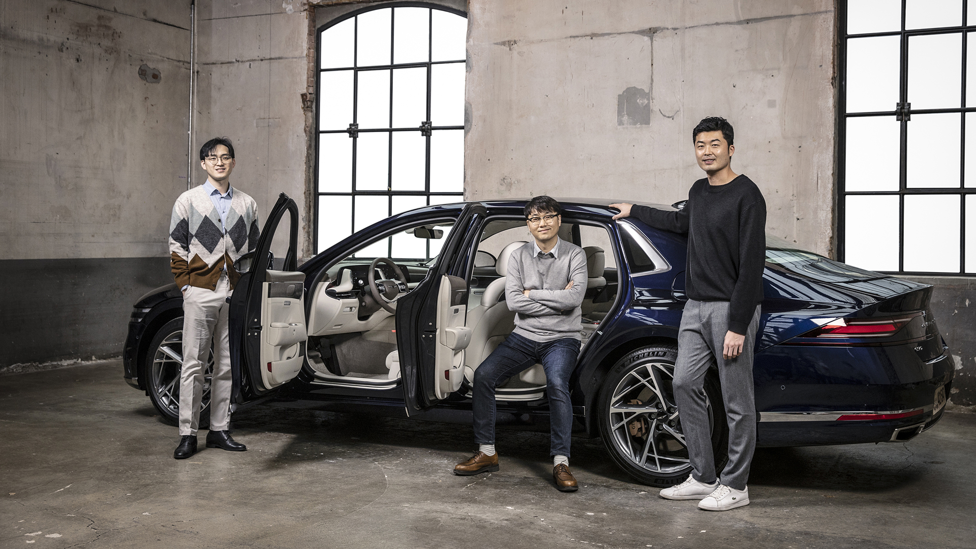 Genesis G90 and three interior designers are posing next to a car