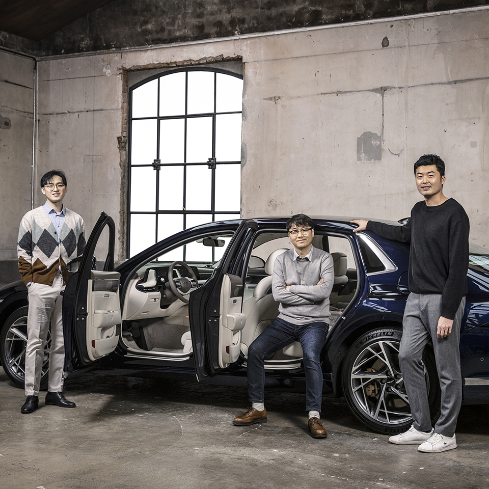 Genesis G90 and three interior designers are posing next to a car