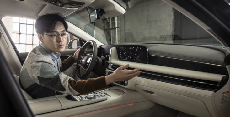 Senior Researcher Janghyuk Ahn is pointing his hand at the extended dashboard top.