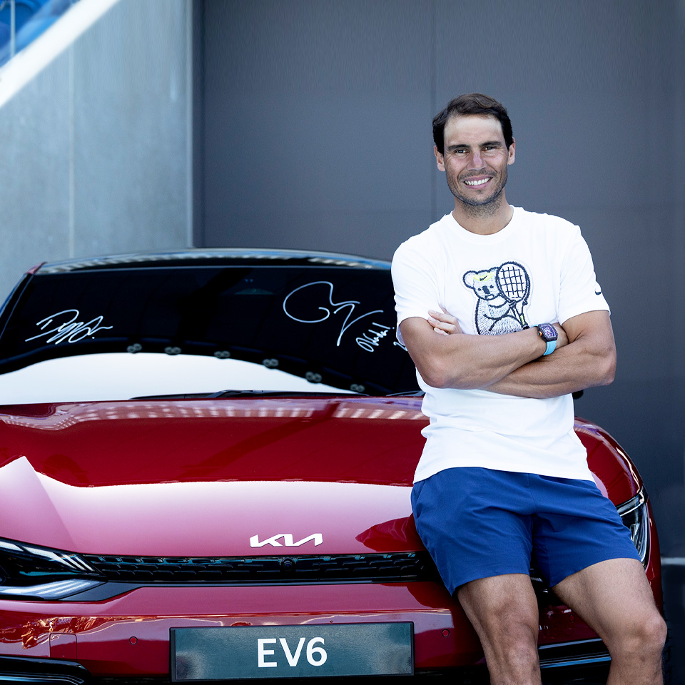 라파엘 나달 선수가 기아의 첫 전용 전기차 EV6 후드에 걸터 앉아 웃고 있다