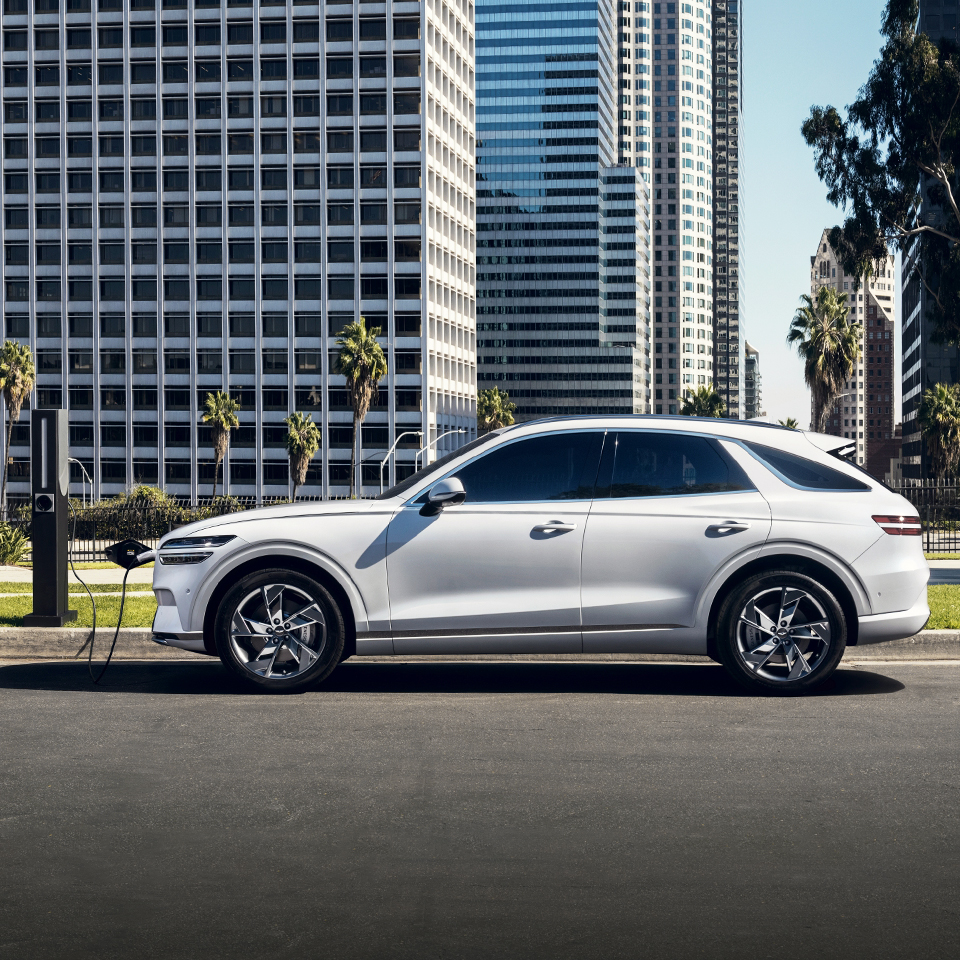 고층 건물이 있는 도심을 배경으로 주차되어 있는 GV70 전동화 모델의 측면 모습