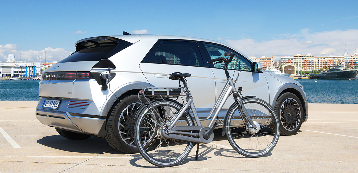 강변을 배경으로 주차되어 있는 아이오닉 5와 V2L 기능을 사용해 충전 중인 전기 자전거의 모습