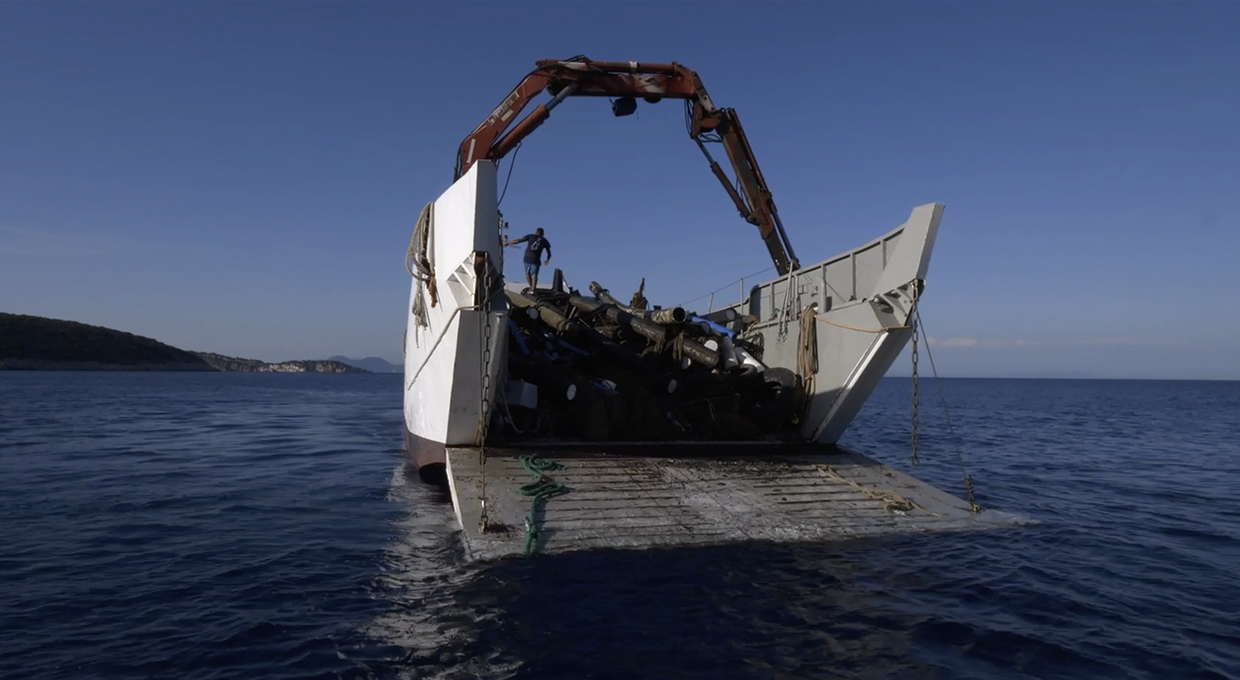 Ship with a crane and an open tailboard loaded with lots of ocean waste