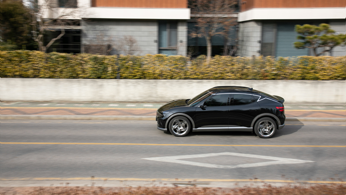 도심의 단독 주택가 주변 도로를 달리는 GV60의 모습