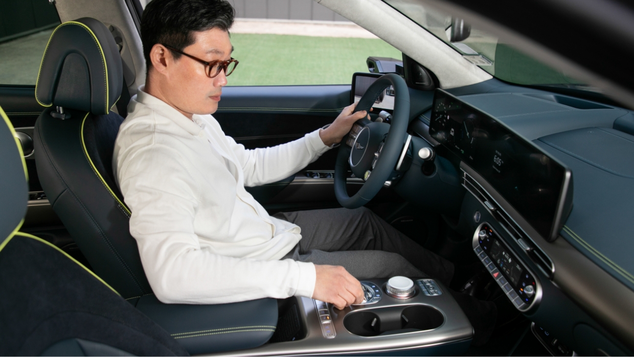 장우영 씨가 GV60 운전석에 앉아 변속 다이얼로 전환되는 크리스탈 스피어를 만지고 있다