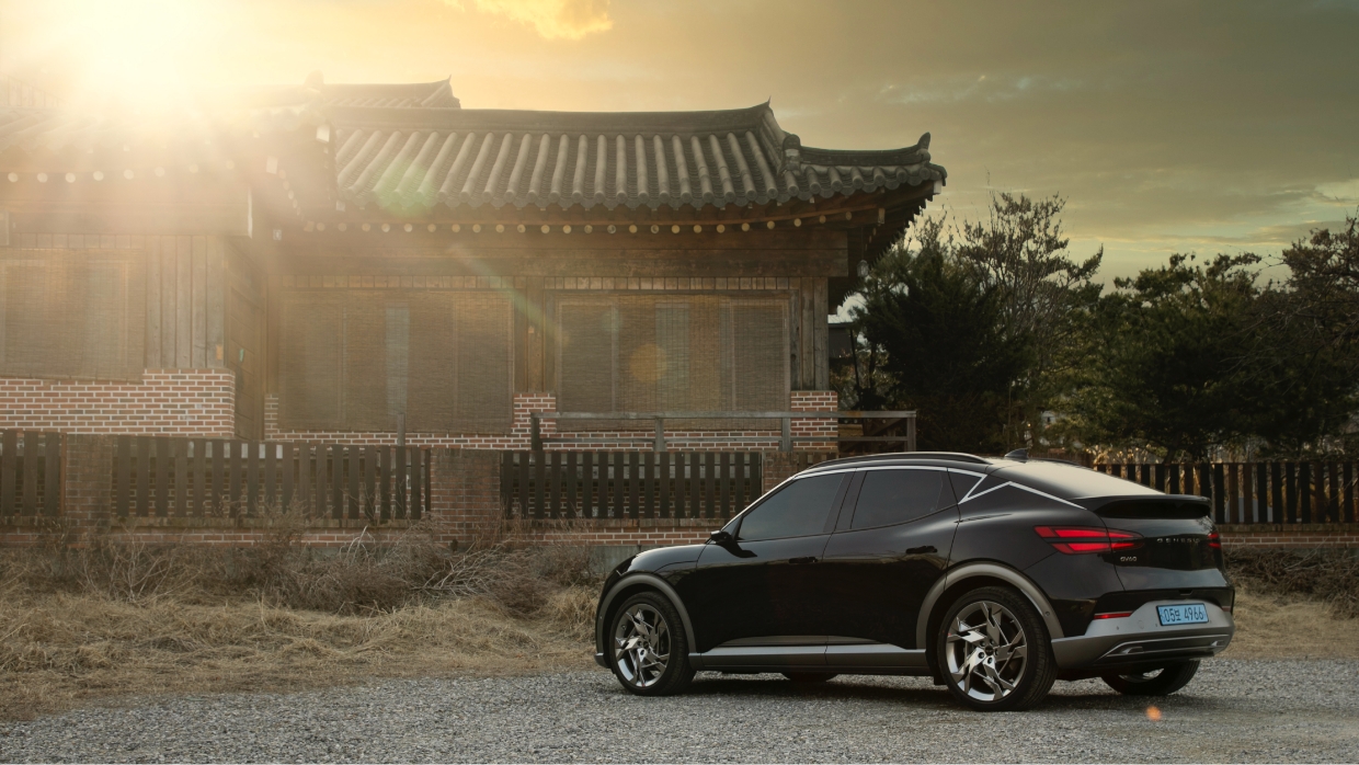 GV60가 고즈넉한 한옥을 배경으로 석양 빛을 받으며 서 있다