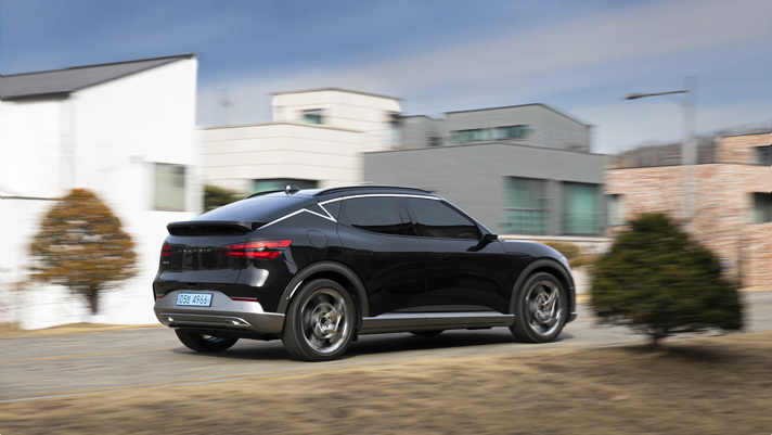 The rear of the GV60 running on the road in the downtown residential area
