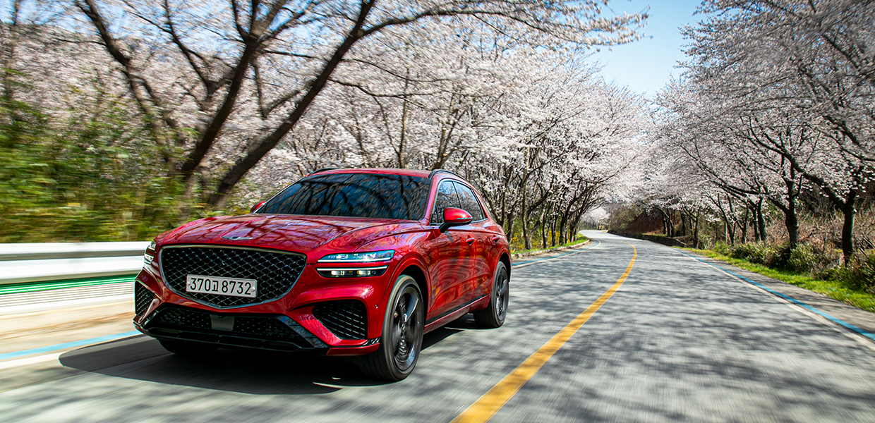 GV70가 벚꽃 나무 사이로 질주하는 모습