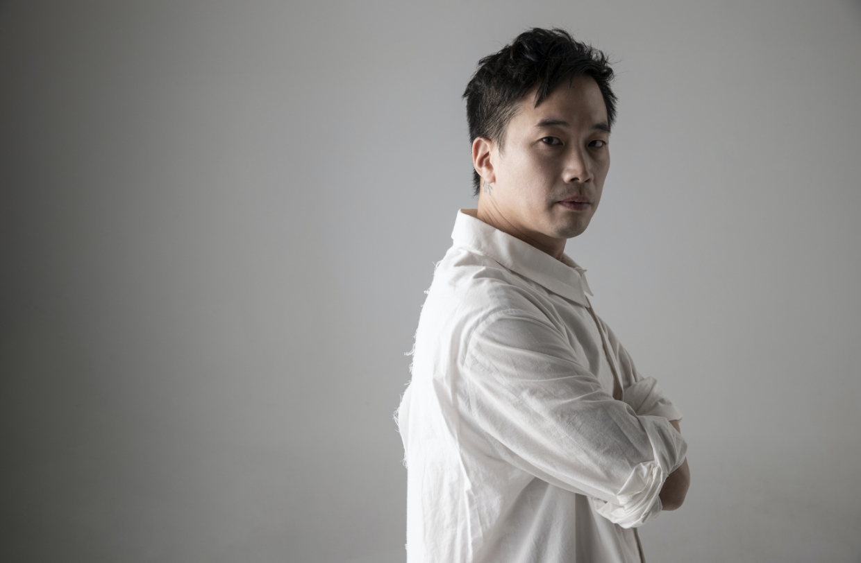 음악감독 정재일이 흰색 셔츠를 입은 채 팔짱을 낀 모습